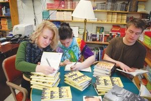 New books on “tolerance” are available at Cook County High School, thanks to a grant from the Grand Marais Lions and Lioness clubs. These books chronicle success stories of young people who have overcome poverty, prejudice, prison records, and autism. Unpacking the books and numbering them to be placed on the shelves are (L-R) Autumn Sturm, Julia Larsen, Jack Viren.