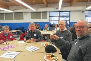 Above right: Tane Danger (left) and Brandon Boat, members of The Theater of Public Policy, worked together to elicit plenty of laughs. Above left: “What the Health?” attendees were invited during dinner to leave comments on the paper-covered tables regarding what makes a community healthy. Left: Members of The Theater of Public Health (L-R) Carmen O’Halloran, Kelly Kohlbacher, Jim Robinson, and Brandon Boat listened to a discussion on community health to incorporate into the following round of improv comedy.