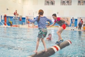 Staying low and carefully working the log back and fourth, Ali Duclos (right), sent her competitor into the drink at the Harold Fischer log rolling tournament held in Hudson, Wisconsin. Duclos finished second in the U-10 girls division.