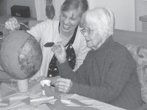 Care Center residents created—and then smashed—a piñata to celebrate May. Above: Marce Wood and Ethel Leng put the finishing touches on the colorful piñata. Left: Bob Heideman takes a swing at the piñata while frequent Care Center visitor Woody looks on.