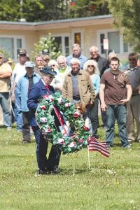 After a weekend of on and off rain showers, the skies cleared for the Monday, May 30 Memorial Day observance on the Cook County courthouse lawn. American Legion Post 413 Auxiliary member Edie Mattson places a wreath at the veterans memorial.