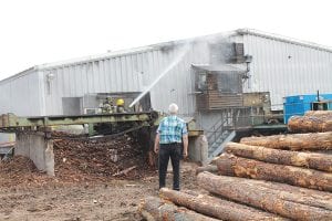 Hedstrom Lumber Company President Howard Hedstrom watches as firefighters hose down the smoldering roof of the main sawmill. Firefighters from Maple Hill, Grand Marais, Colvill, Lutsen and Tofte were called to fight the fire on Wednesday, June 8.