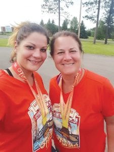 Ashley Howard-Larsen and her mother Jane Howard show off their finisher medals for completing the Garry Bjorklund half marathon.