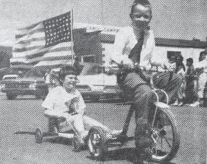 The weather on July 4, 1961 was described as “perfect” for the annual parade in downtown Grand Marais. Shown in this photo is Dale Hedstrom pulling his sister Margaret, who is proudly displaying the flag. In addition to the children’s decorated entries, the parade also included the high school band, Boy Scouts, costume and humorous divisions, vehicle groups and bicycles.