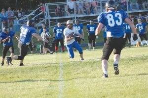 Above: Carrying the football, fleet-footed Andy Borud takes the ball up field against the Blue team for a nice gain. Left: Looking at a sea of white jerseys, Mark Marxen looks for an opening, picking up about five hard-earned yards on the play.