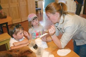 Bo and Sophia Christianson listen intently as Chik-Wauk Nature Center program director Jacqueline Mallison shows them how to identify an animal’s footprint. Bo and Sophia attended the Nature Center’s grand opening with their parents, Cory and Rachelle Christianson.