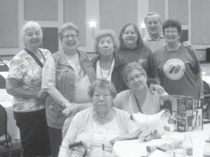 Grand Portage Elders enjoyed a trip to the Wisdom Steps Conference. Above: Some attendees were (L-R, seated) Doris Blank, Polly James. (L-R, back) Carol Hackett, Patty Winchell-Dahl, Ellen Olson, Ellie Altman, Bob and Eddie Hertzberg. Left: Ellen Olson and Eddie Hertzberg at the Wisdom Steps traditional clothing fashion show. Eddie is wearing the ribbon shirt she purchased from Ellen about 30 years ago.