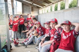 Above: The first place Twins were ‘chillin’ in the clubhouse during one of their recent Little League games. Left: Coach Jared Smith huddles his excited Parent Pitch team and they touch gloves before a game.