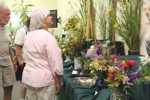 Top: Guests at the Grand Marais Garden Club Flower Show on July 21 enjoyed the interesting Nature’s Symphony arrangements. Above left: Lovely lilies were part of Marilee Mielke’s floral display. Above right: Part of the fun is reading the notes about the floral bouquets.