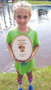 Holding a plaque almost as big as she is, Alexis Plummer was a happy second-place finisher in the co-ed U-7 log rolling championships.