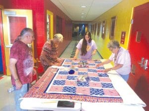 Dido Swader, Elder Advisory Board chairman checks out the beautiful Elder raffle quilt as Board Member Carol Hackett, Treasurer, Jaye Clearwater and Ellen Olson put on the finishing touches. Not pictured is Betty Hoffman who sewed the quilt top.