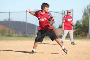 As first baseman Patrick Pierre looks on, Daunte Deschampe gets ready to deliver a pitch in the championship game.