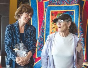 Care Partners Executive Director Kay Grindland (left) and Board Chair Jayne Johnson prepare for the quilt raffle draw. Bonnie Schudy, Chik- Wauk Museum and Nature Center director, won the beautiful quilt made by Carol Harris.