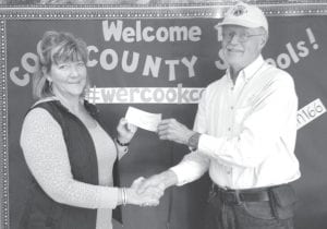 Grand Marais Lions Club President Mike Carlson hands a check for $3,000 to ISD 166 School Board Chair Jeanne Anderson to help pay for teacher training in the Orton- Gillingham reading methods. Thirty-seven teachers from all Cook County schools met for four days of intensive training in methods to teach reading at the elementary level.