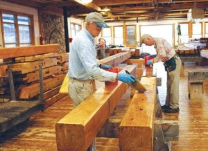 Above: Nearly done! Mike Carlson and Les Edinger apply stain to the massive timbers that will shelter a watercraft exhibit at Chik- Wauk Museum and Nature Center. Left: Volunteer Bill Douglas carefully uses the mortise tool during the timberframe construction at North House Folk School.