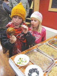 Right: Gunflint Mercantile is always a great place to be on the Saturday of Moose Madness. Children (and adults who are kids at heart) come into the store and take part in a variety of fun-filled activities. Here one curious youngster watches as an older sibling carefully decorates a carmel apple.