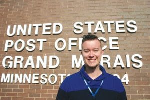 Matt MacFarlane breaks a big smile in front of his new office. Taking over for former Postmaster Frank Letho, the 27-year old MacFarlane is excited to serve the postal needs of Grand Marais.