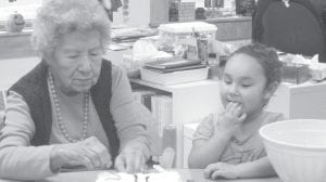 Ellen Olson decorating cakes for the Halloween Carnival with help from Nevaeh. In all, 42 cakes were baked and decorated for the cake walk.