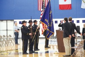 Above: Catching a salute from Dr. Bill DeWiit, American Post Legion 413 Color Guard presented the flags at the high school Veterans Day tribute. Right: Arms folded, Dick Nelson sits next to his father Willard Nelson. At 102 years old, Willard is believed to be one of the oldest living veterans in Cook County.