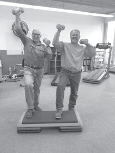 It’s never too late to prepare for the Olympics. Or to get in shape for a little stroll around the block. Here, two excellent strapping athletes, Skip Lamb (left), and Steve Michaud are pressing some pretty impressive weights over their head while they rigorously stepped up and down on a mat. The two were working out at the Birch Grove Community Center workout room the other day.