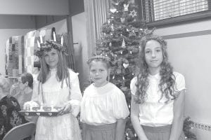 Bethlehem Lutheran Church hosts Julefest each year. The Scandinavian event features a visit from Lucia, who wears a crown of candles and brings a tray of saffron buns to share. The event is held near the shortest day of the year to honor St. Lucia and celebrate the return of the light. Pictured at last year’s Julefest ceremony are, from left, Paige Everson as Lucia, and attendants Taylor Everson and Cecelia Chmelik.