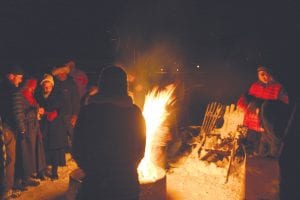 Top: Folks gather around a bonfire to warm up and toss in their gloomies. Above: The final panel of the puppet show encourages the crowd to head to the bonfire. Left: After shedding some layers and gloves, people gathered around tables to share in good food and conversation.