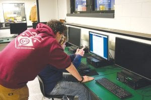 While some students build the robot, other kids work on programming. David Blackburn looks over Noah Works shoulder at the computer screen as the two search for the best computer language they will use to program the multi-tasked robot.