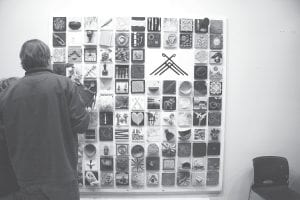 Onlookers pore over the details of handmade tiles. Each tile represents the work of someone either currently or formerly working at North House and features wood carvings, felted patches, and even working gears.