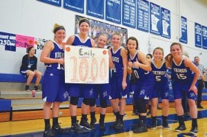 With her happy teammates standing with her, Vikings’ senior center Emily Jacobsen is all smiles as she holds up the sign commemorating her 1,000 points as a Viking. From L-R: Hannah Toftey, Emily Jacobsen, Sophie Eliasen, Sarah Toftey, Abbie Crawford, Maya McHugh, and Bayley Cox.