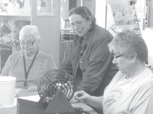 ENP staff, Carol Hackett, Shirley Stevens and first time bingo caller and full-time cook Polly James. Polly appears to be puzzling over a number while Shirley and Carol smile patiently.