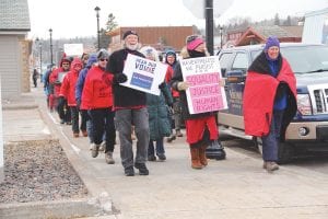 Cold and wind couldn’t keep the marchers away. More than 40 people, many who belong to Arrowhead Indivisible, came out in support of International Women’s Day, Wednesday, March 8. The group gathered at noon at Harbor Park. Many wore red and several spoke about the value women add to our socio-economic system, while receiving lower wages and experiencing greater inequities, vulnerability to discrimination, sexual harassment and job insecurity. While there were speeches, some women took the day off from paid and unpaid labor. Others avoided shopping for one day, with an exception for shopping at small, women and minority owned businesses. After meeting at Harbor Park the group marched from East Bay to Java Moose, “just to show solidarity with women’s rights around the world,” said Denny FitzPatrick. Right: Pat Campanaro was one of the speakers in Harbor Park.