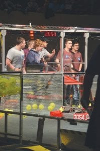 Far left: CCHS teammates (L-R) Billy Hackett, Noah Roth, David Blackburn and in the back Noah Works operate Ice Storm, the team’s robot. Above: The competition was fast and furious in Duluth at the DECC for the 2017 robotics competition. Left: John Vander Heiden adjusts a piece on the robot.