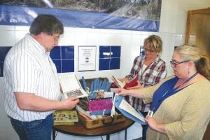 Bruce Johnson, Julie Viren, and Jana Larson (checkered shirt) all took delight in looking at the treasures found in the 20-year-old time capsule recently opened at the school.