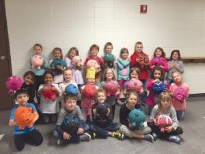 Sawtooth first-graders found a great use for old Cook County News-Heralds. They made papier mache piggy banks out of them! Above: Betsy Jorgenson and Natalie Shaw’s class poses with the entire pretty painted “piggies” they made. Far left: Three children work carefully as they fashion the bodies of their piggy banks. Left: Some paint on the nose of Ashtyn Nelson didn’t affect her glee while painting her piggy bank.