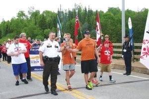 It was quite a sight to see as a large contingency of Thunder Bay police and members of the Special Olympics Canada joined forces with Cook County Law Enforcement, Cook County I.S.D. 166 Unified Club, and Special Olympics Minnesota at the Pigeon River Border crossing on Monday, June 19, on a unified torch run from Thunder Bay that will end in the Twin Cities on June 23, just in time for the Minnesota Special Olympics games. Cook County Sheriff Pat Eliasen is in the white shirt in front in this picture.