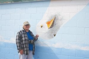 It might be said that the public restrooms at city hall might be going to the birds, but they look great! Sarah and Anna Hamilton, Gail Anderson and Jayne Richards (above, who painted the seagull) have done much of the work. Local carpenter Kelly Pusc volunteered to put up the tin around the top of the building and his wife Chelsea did some painting inside the building. Sarah found the leftover tin at the Cook County/Grand Marais airport and repurposed it. Dave Woerheide painted the new sign.