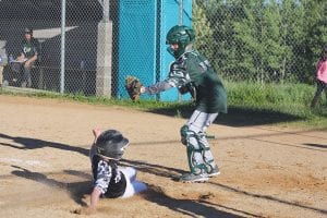 Sliding hard, this base runner beat the throw to home plate while the catcher waited expectantly.