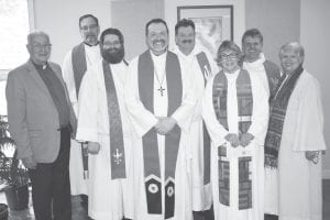 Above: After the ordination ceremony all of the ministers are smiling but the biggest smile of all is from Pastor Daren Blanck. Right: Pastor EvaLyn Carlson, reading to Daren, was one of the pastors who helped to conduct the ordination.