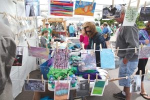 Downtown Grand Marais was a very busy place last week during the two-day Grand Marais Arts Festival. People from near and far flocked to the closed streets to peruse the paintings, pottery, photographs, jewelry, glassware, etc., or to participate in making their own T-shirts, paper lanterns, clay sculpture, or to pick up a paint brush and help with the “Imagine the Northoods: A community paint-by-number mural project,” all the while listening to musicians playing in Harbor Park. See more of the Grand Marais Arts Festival on page A9.