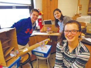 CCHS physical science students finished the school year making Rube Goldberg projects to learn about motion and energy. The projects used materials generously provided by a grant from the Lioness Club. Standing with their “Raising the Raisins” project are, from left, Trent Spry, Sarah Slivinski, and Abbie Crawford.