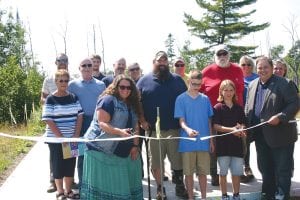 The Theo Rex family from Buffalo, Minnesota will soon have a new home built on the North Road in Hovland because of the efforts of Journey Home, an organization located in North Oaks, Minnesota started by Blake Huffman. Theo served 15 years in the Army, leaving the service in 2014 as a disabled veteran. Journey Home has built more than 40 homes for disabled veterans, but the one in Hovland is the farthest from the Twin Cities the group has ventured. Cutting the ribbon on the site their home will be built on are Jamie, Hunter and Ben, with their dad, Theo standing between Jamie and Hunter.