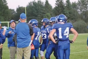 Above: Players huddle around head coach Mitch Dorr (back to camera) and listen as assistant coach Mike Prom gives them some instructions. Left: Junior quarterback Josh Prom rolls out to throw the ball.