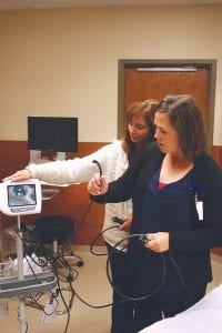 Onscreen, a nurse from Avera talks about the eEmergency services now offered at North Shore Health. RNs Amy Lacina and Shannon Curran examine a breathing tube and the machine it connects to that was installed by Avera.