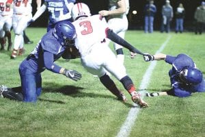 Above: Hanging on by a thread—literally—Dillon Sjogren slowed the Ely running back just enough so that Ethan Sporn could come up and make a big hit on the ball carrier. Left: Busting through the line, Joe Deschampe wrapped up the Ely Timberwolves’ running back in the backfield for a loss on the play. Below left: The defense was the key to the Viking win against Ely. Here Jack Haussner wraps up the ball carrier with Andrew Miller charging in to help on the play.