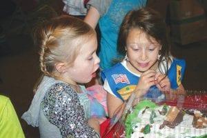 Above: How delicious was this gingerbread decorated cake going to taste? Judging by the looks on these two youngsters’ faces at Santa's Workshop, very scrumptious indeed! Right: Loretta Houglum was doing a brisk business selling her wreaths at the Community Center.