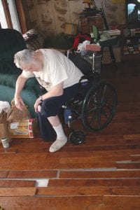 Dave Asproth looks at the floorboards that have come up following a pipe that burst in house. The pipe froze during the recent power outage and Asproth, who is mostly wheel chair bound, spent all night using a shop vac to get the water off of his floor.