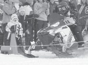 The Cook County Ridge Riders held their annual drag races at Skyport Lodge on Devil’s Track Lake on Saturday, January 27 with a nice turnout of racers who came from near and far and a great crowd was on hand to cheer them on. Right: As the snowmobile powers away from the start Jack Radloff’s expression is priceless. Jack was with his mom, Stephanie Radloff, watching the snowmobiles blaze across Devil’s Track Lake.