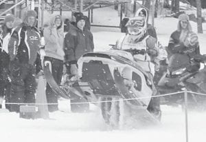 Left: Reminiscent of a motorcycle racer doing a wheelie at the start of a race, this high-powered snowmobile picks up some air and jettisons a rooster tail of snow behind it as the racer powers his machine down the race course.