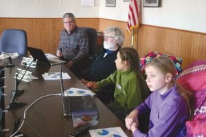 With Grand Marais Public Utilities Commission (PUC) members Karl Hansen (left) and Tim Kennedy looking on, Olya Wright and Naomi Tracy, on the right, gave a presentation at the Feb. 7 PUC meeting. As representatives of the Nordic Nature Group, the two young ladies described what the group was doing to combat the effects of climate change.