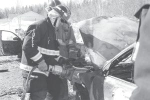 A local firefighter recently received some training using a special cutter he might have to use in a vehicle rescue while below a second firefighter gets assistance putting on an air tank before he enters (potentially) a smoky enclosure.